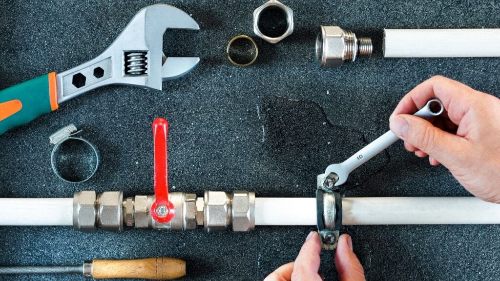 Plumber repairing a pipe valve with an adjustable wrench in Roswell
