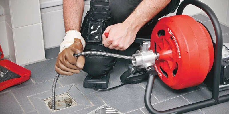 Plumber using a drain-cleaning machine in Roswell